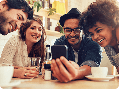 high-yield-contact-rounded Group of friends seated at table looking at phone